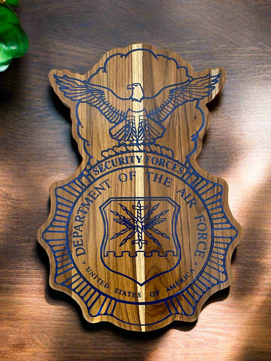 Security forces shaped teak wood plaque set on a table top with plants near by to show the contrast between the wood and the blue epoxy